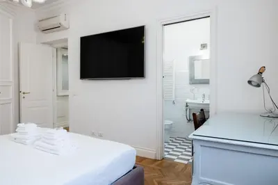 a white bedroom with a flat screen tv on a wall at Candy Lodge in Rome