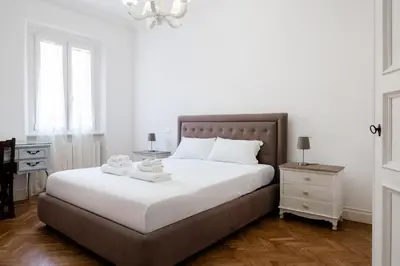 a bedroom with a bed with white sheets and a chandelier at Candy Lodge in Rome