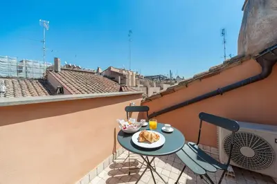 a table with a plate of food on a balcony at Renovated Luxury Sweet Penthouse - Campo Dei Fiori in Rome
