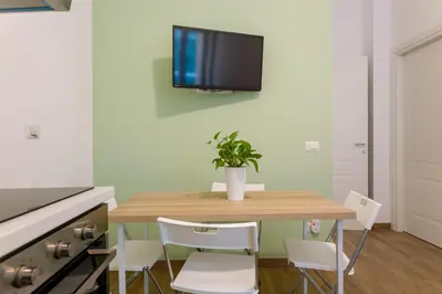 a dining room table with chairs and a tv on the wall at Maison Manú - Vaticano in Rome