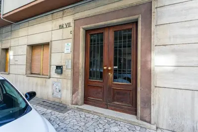 a building with a wooden door with a car parked outside at Maison Manú - Vaticano in Rome