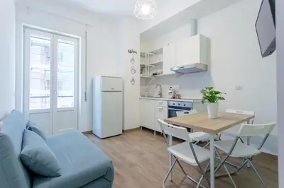 a kitchen and dining room with a table and a blue couch at Maison Manú - Vaticano in Rome