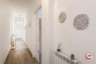 a hallway with white walls and wood floors and a mirror at Domus Latina heart San Giovanni in Rome