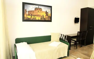 a living room with a table and a green couch at Le tue Notti a San Pietro in Rome