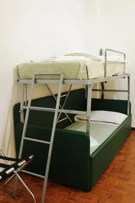 a bunk bed with a green couch and a chair at Le tue Notti a San Pietro in Rome