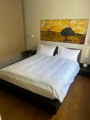 a bedroom with a white bed with a painting on the wall at Casa Jacomini in Rome