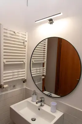 a bathroom with a round mirror above a sink at Boutique apartment 10 min to Colosseum and Termini in Rome
