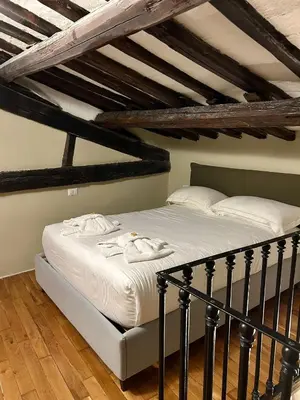 a bedroom with a bed with white sheets and wooden floors at Trastevere Luxury Apartment in Rome