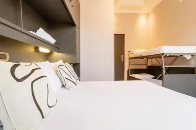a room with a bed with white sheets and pillows at Cunabu Castro Pretorio in Rome