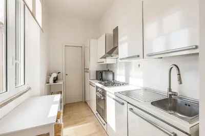a white kitchen with white cabinets and a sink at ATRHOME- Penthouse Tritone in Rome