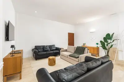 a living room with a black leather couch and a tv at ATRHOME- Penthouse Tritone in Rome