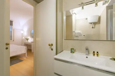 a white bedroom with a white bed and a mirror at Rome Central Suite via Porcari in Rome
