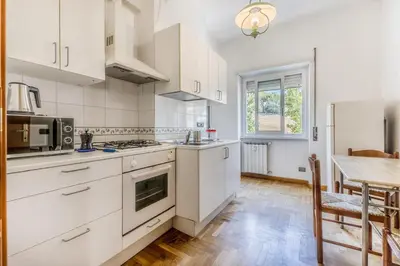 a kitchen with white cabinets and a table and a tableablish at Guest House Ionio in Rome