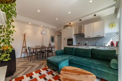 a living room with a green couch and a kitchen at GuestHost - Colorful Apt in Vintage-Modern Style in Rome