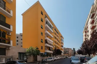 a yellow building on a street with parked cars at GuestHost - Colorful Apt in Vintage-Modern Style in Rome