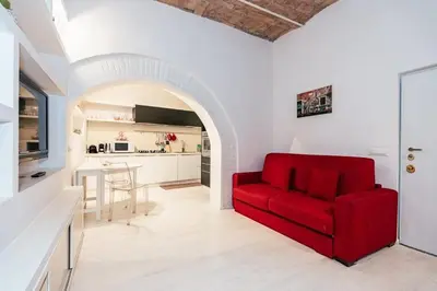 a red couch in a living room with a kitchen at Roma Suite Piazza Navona in Rome
