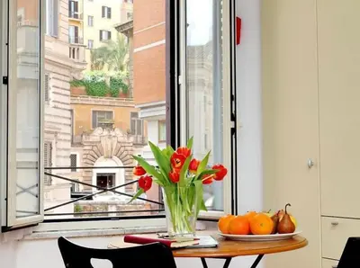 a vase of flowers on a table in front of a window at 600mt To Colosseum in Rome