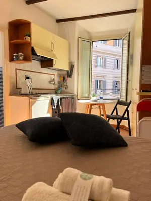 a bedroom with a bed with two pillows and a kitchen at 600mt To Colosseum in Rome