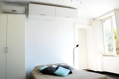 a bedroom with white walls and a bed with pillows at Rome Center Attic Penthouse in Rome