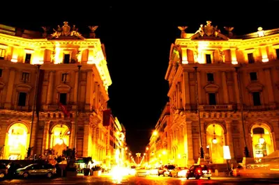 two large buildings at night with lights on them at Rome Center Attic Penthouse in Rome