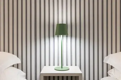 a green lamp on a table next to two beds at Rome Capital Apartments in Rome