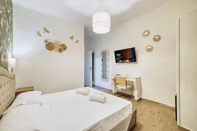 a white bedroom with a bed and a desk at Radio Suites in Rome