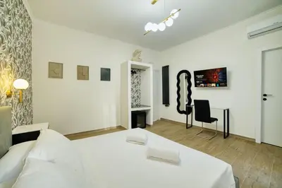 a white bedroom with a bed and a chair at Radio Suites in Rome