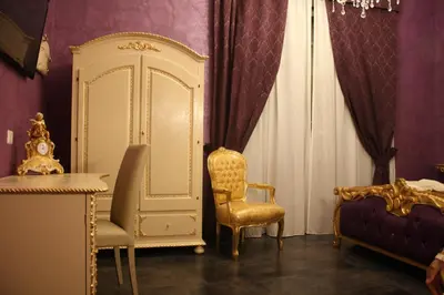 a room with a bed and a chair and a cabinet at Pope's Suites in Rome