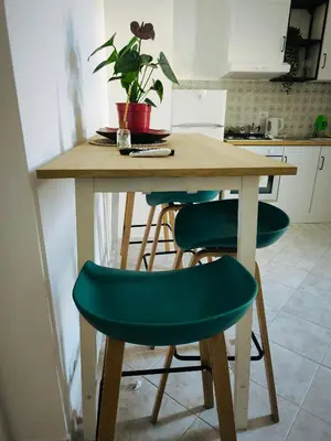 a kitchen with a wooden table with green chairs at the italians house in Roma San Lorenzo in Rome