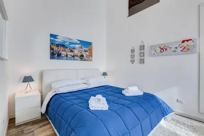 a white bedroom with a blue bed with a blue comforter at Apartment near the Vatican in Rome