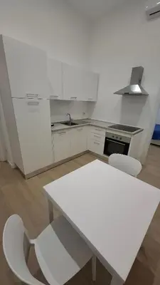 a white kitchen with a white table and chairs at Pigneto New collection 3 Perugia in Rome