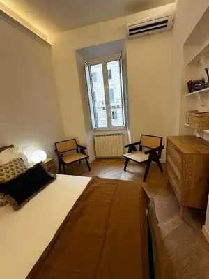 a bedroom with a bed and two chairs and a window at The Roman Retreat - 2BDR Colosseum Monti district in Rome