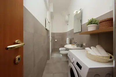 a bathroom with a toilet and a sink and a washing machine at Circo Massimo House by Luxury Getaways in Rome