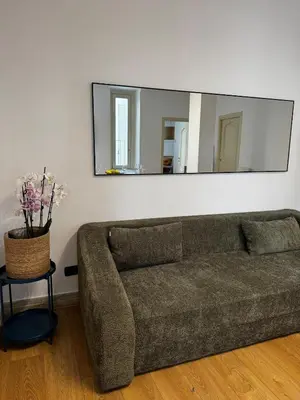 a couch in a living room with a large mirror at Roman Holiday Escape 2BDR Spanish steps and Trevi in Rome
