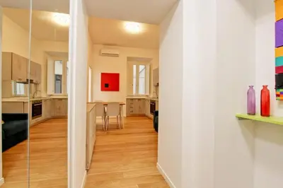 a kitchen and dining room with white walls and wooden floors at Poliziano Boutique Apartment in Rome