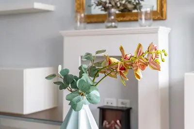 a white vase with flowers in it next to a fireplace at iFlat Charming Hideaway Apt by the Vatican in Rome
