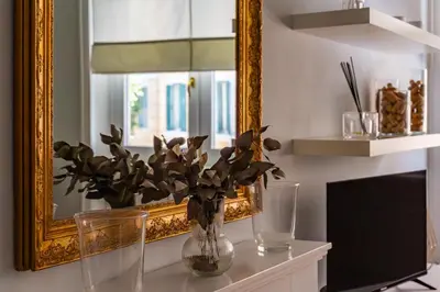 a vase with flowers on a table in front of a mirror at iFlat Charming Hideaway Apt by the Vatican in Rome