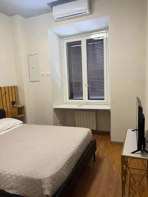a bedroom with a bed and a television and a window at Locanda di Trastevere in Rome