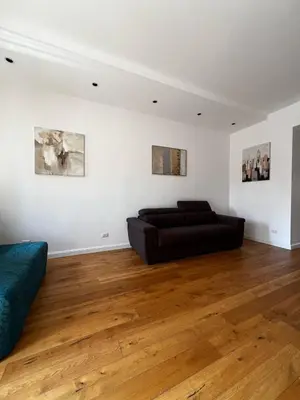 a black couch in a white room with wooden floors at Zaffiro FIUME charming apartment in Rome