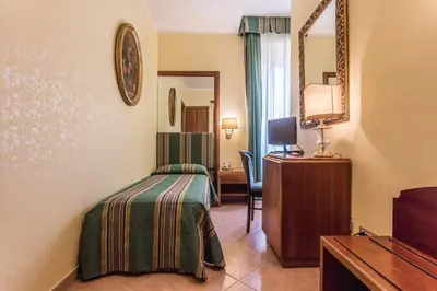 a bedroom with a bed and a desk and a mirror at Raeli Hotel Lazio in Rome