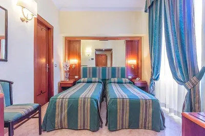 a hotel room with two beds and a mirror at Raeli Hotel Lazio in Rome