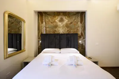 a bedroom with a large white bed with a mirror at Antinous Suites in Rome
