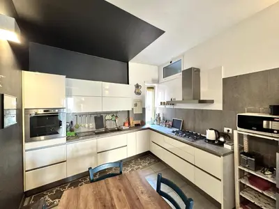a kitchen with white cabinets and a wooden table at Casa Fradella in Rome
