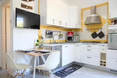 a kitchen with white cabinets and a table with chairs at Wanderlust RHome - Scopri Roma e sogna il mondo! in Rome