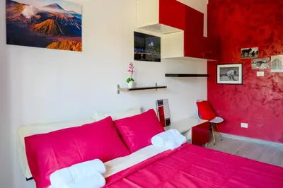 a bedroom with a pink bed and a red wall at Wanderlust RHome - Scopri Roma e sogna il mondo! in Rome