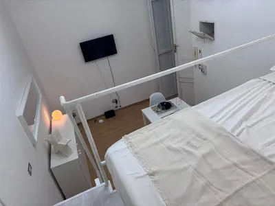 a white room with a bed and a flat screen tv at Golden Suite - un piccolo loft nel cuore di Roma in Rome