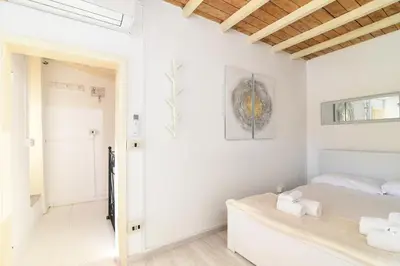a white bedroom with a bed and a painting on the wall at Navona studio with terrace Backpackers in Rome