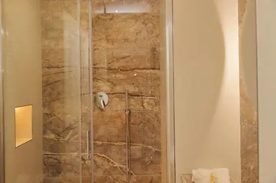 a shower in a bathroom with a stone wall at Holy Mary Lovely Apartment in Rome