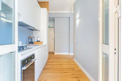 a kitchen with white cabinets and a wooden floor at Luciano Boutique Apartment in Rome