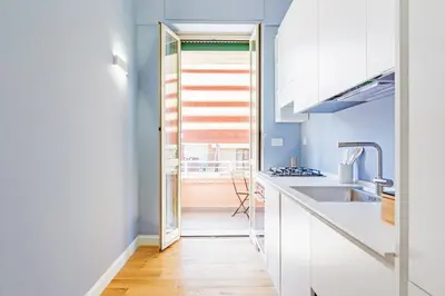 a kitchen with blue walls and white counters and a sink at Luciano Boutique Apartment in Rome